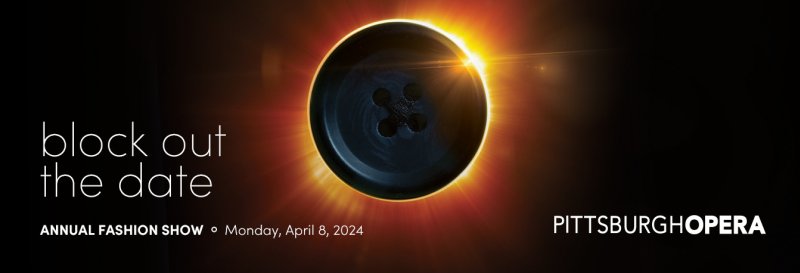 A black button with four holes, glowing with a bright orange and yellow halo against a dark background, resembling a solar eclipse.