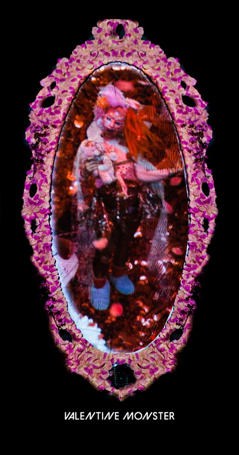 Digital artwork featuring a blurred figure in an oval frame of pink and white flower petals, set against a black background. The figure wears blue shoes and has red hair.