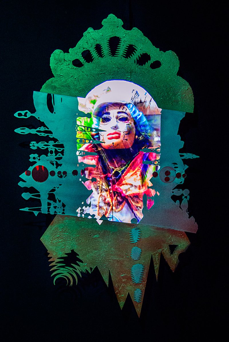 Digital artwork on black: A central portrait of a person in a mask with glitch effects, surrounded by green abstract shapes with textured surfaces.