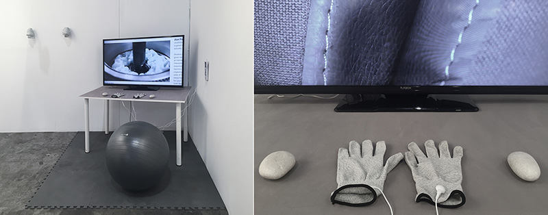 Installation with a TV displaying a hand exercise, gray exercise ball, gloves, and stones on a mat.